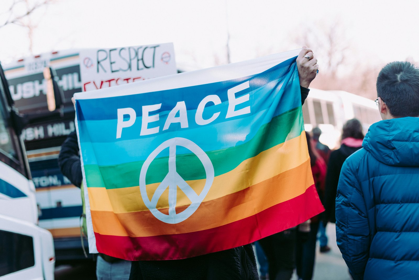 Demonstrierende mit Regenbogenflagge auf der PEACE (Frieden) steht.