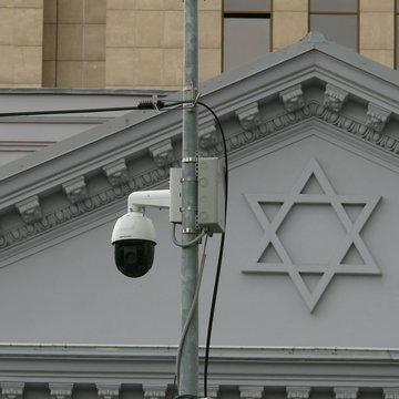 Ein Gebäude an dem ein Davidstern angebracht ist im Hintergrund, davor eine Überwachungskamera