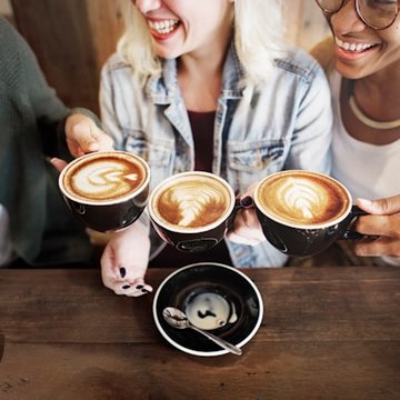 Drei Frauen halten Cappuccinotassen.