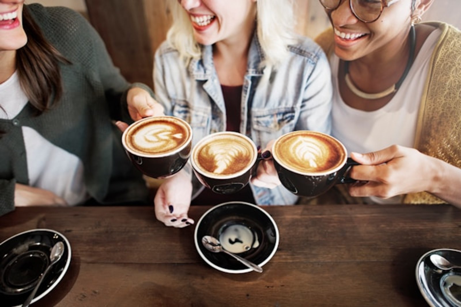 Drei Frauen halten Cappuccinotassen.