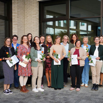 Eine Gruppe von hauptsächlich Frauen steht nebeneinander und lächelt in die Kamera.