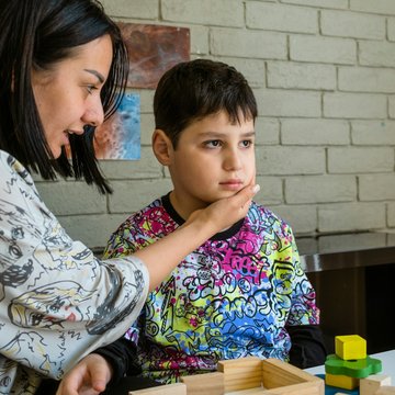 Frau spielt mit einem Kind an einem Tisch