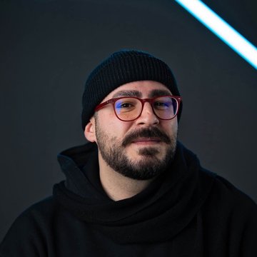Ronnie Darwish in schwarzem Hoodie und schwarzer Mütze vor einem dunklen Hintergrund.