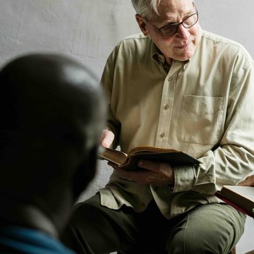 Eine Gruppe von Menschen sitzt im Kreis und liest die Bibel.