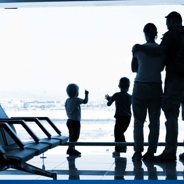 Eine Familie steht wartend an einer Fensterfront im Flughafen.