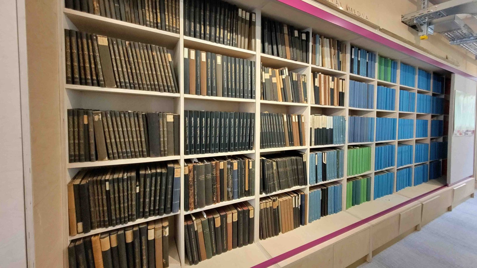 Ein Bücherregal mit großen Bücherbänden in verschiedenen Farben.