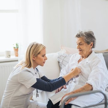 Pflegekraft hört Seniorin mit Stethoskop ab.
