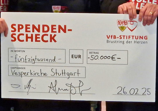 Ein Spendenscheck zeigt die Summe von 50 Tausend Euro, die der VfB an die Stuttgarter Vesperkirche spendet.