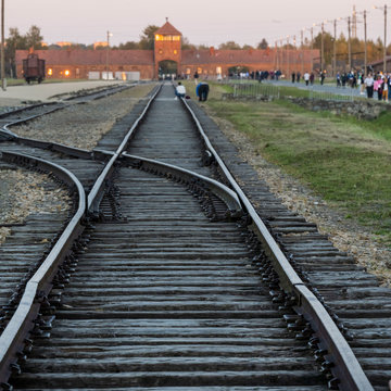Gleise führen auf ein Gebäude des Konzentrationslagers Auschwitz-Birkenau.