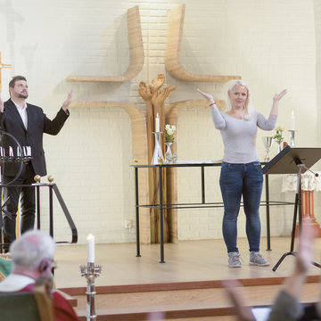 David Fraser und Marianne Kolik stehen nebeneinander und gebärden in einem Gottesdienst