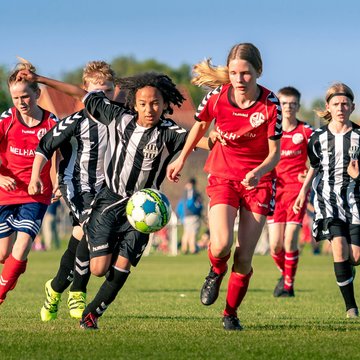 Mädchenfußballmannschaft rennt einem Ball hinterher auf dem Fußballplatz