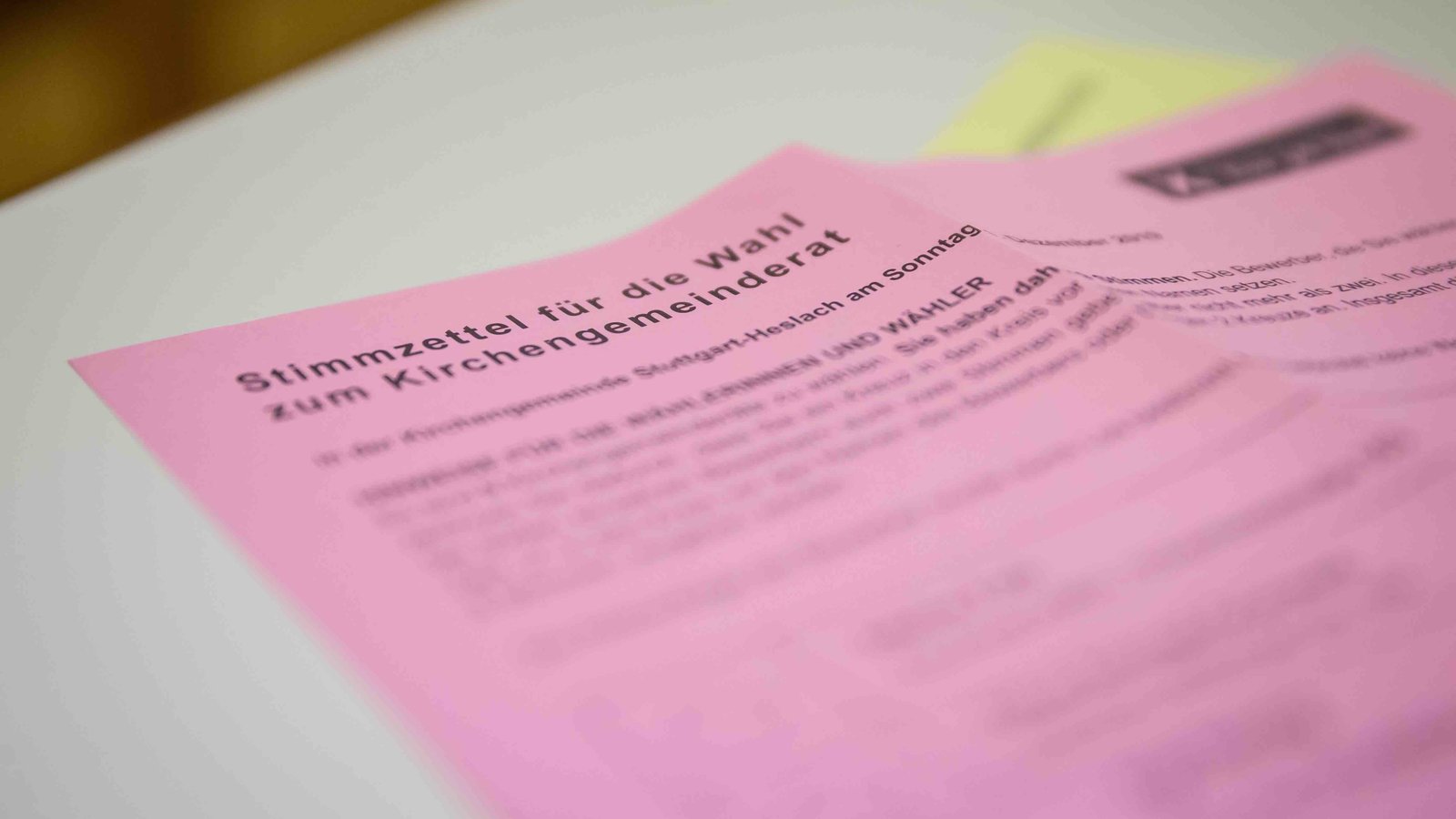 Ein rosa Stimmzettel für die Wahl zum Kirchengemeinderat liegt auf einem hellen Tisch.