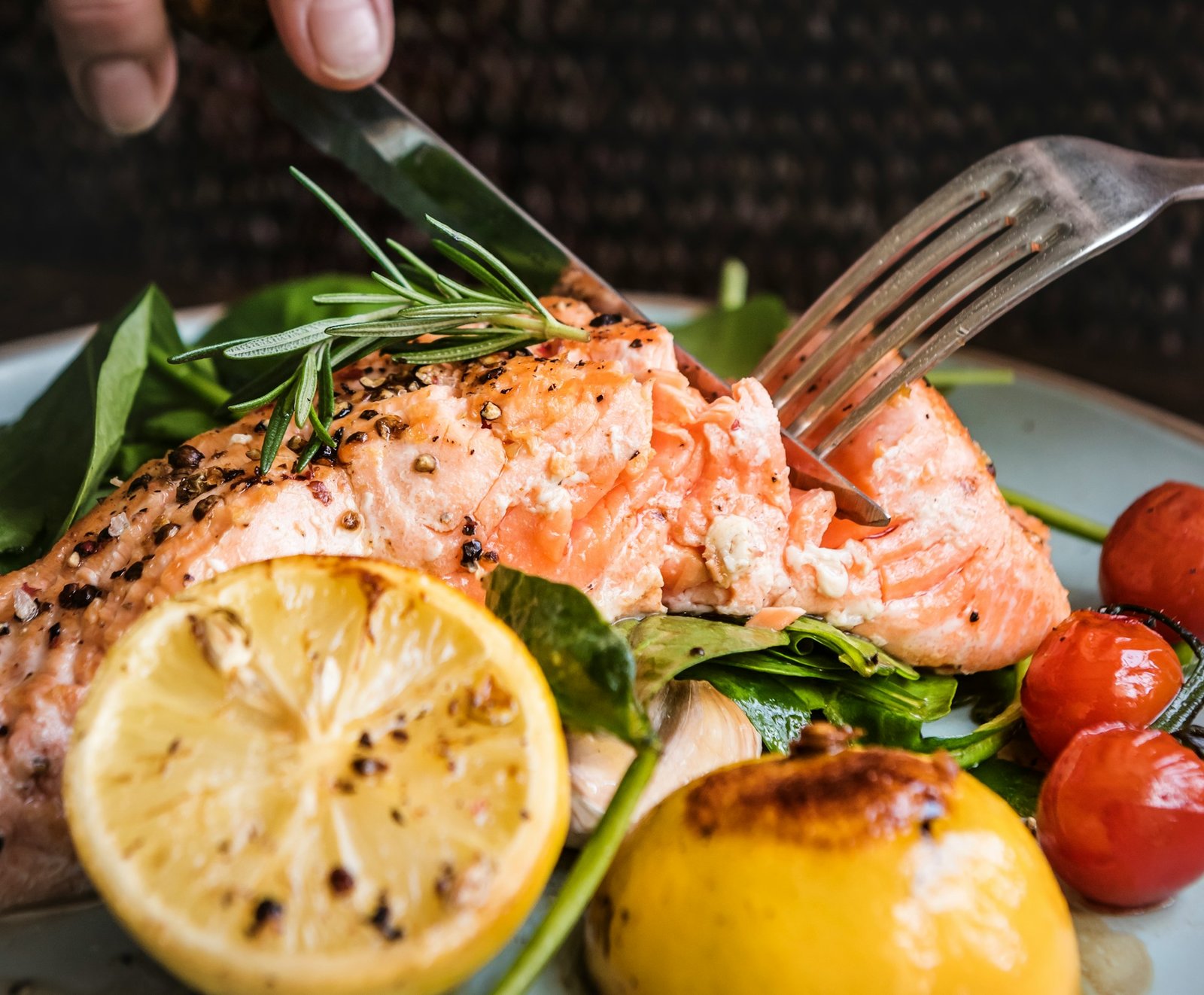 Ein Teller mit einem gebratenen Lachsfilet, Zitronen und Tomaten