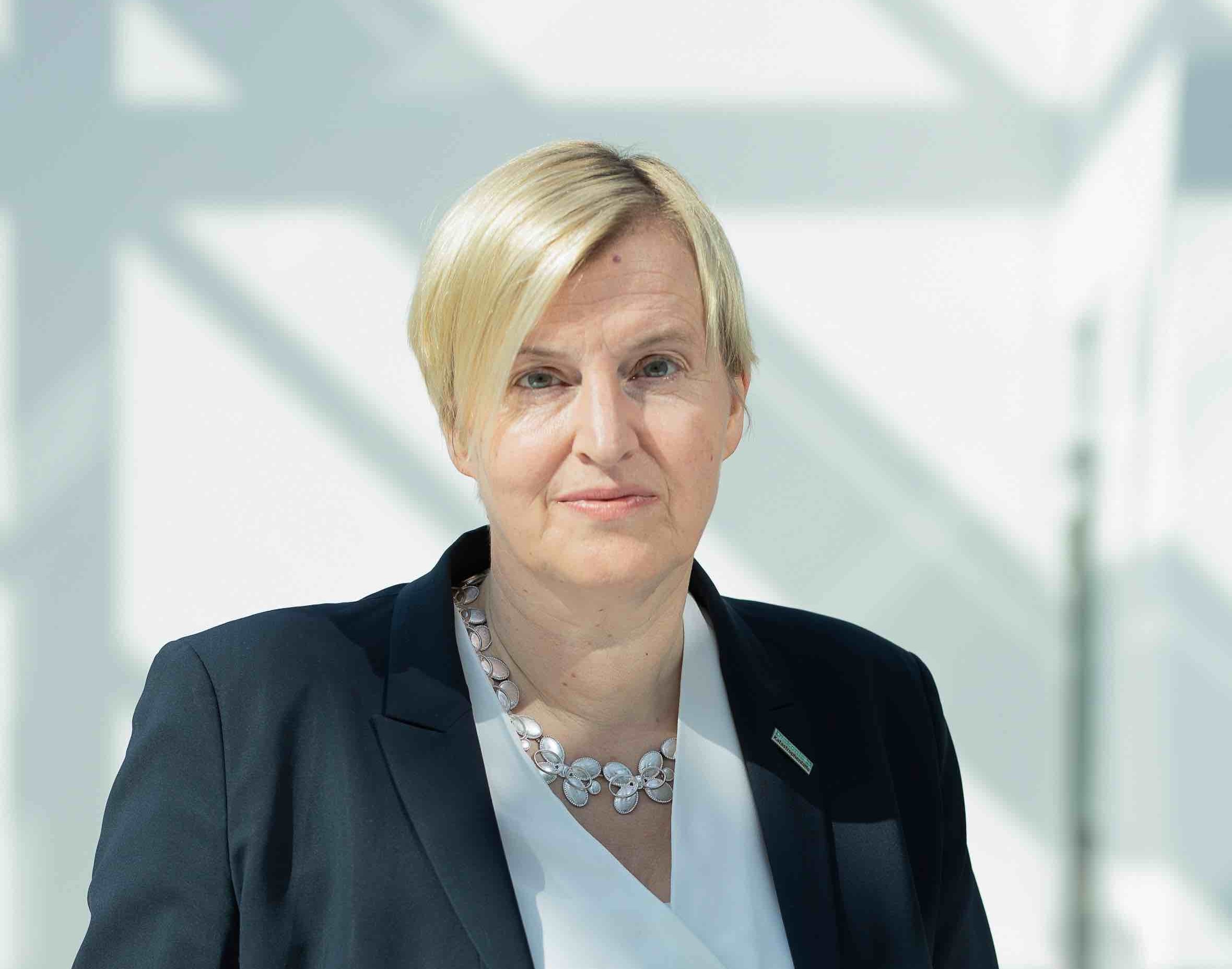 Porträt von Dagmar Pruin mit kurzen blonden Haaren trägt eine weiße Bluse und einen schwarzen Blazer. 