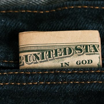 In einer Jeanshose steckt eine zusammengefaltete Dollarnote