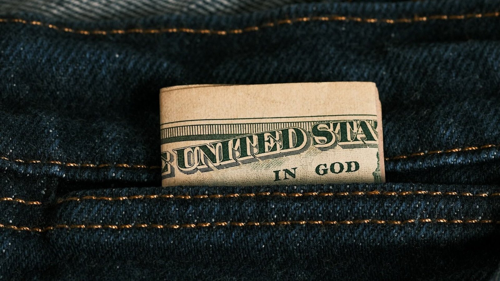 In einer Jeanshose steckt eine zusammengefaltete Dollarnote
