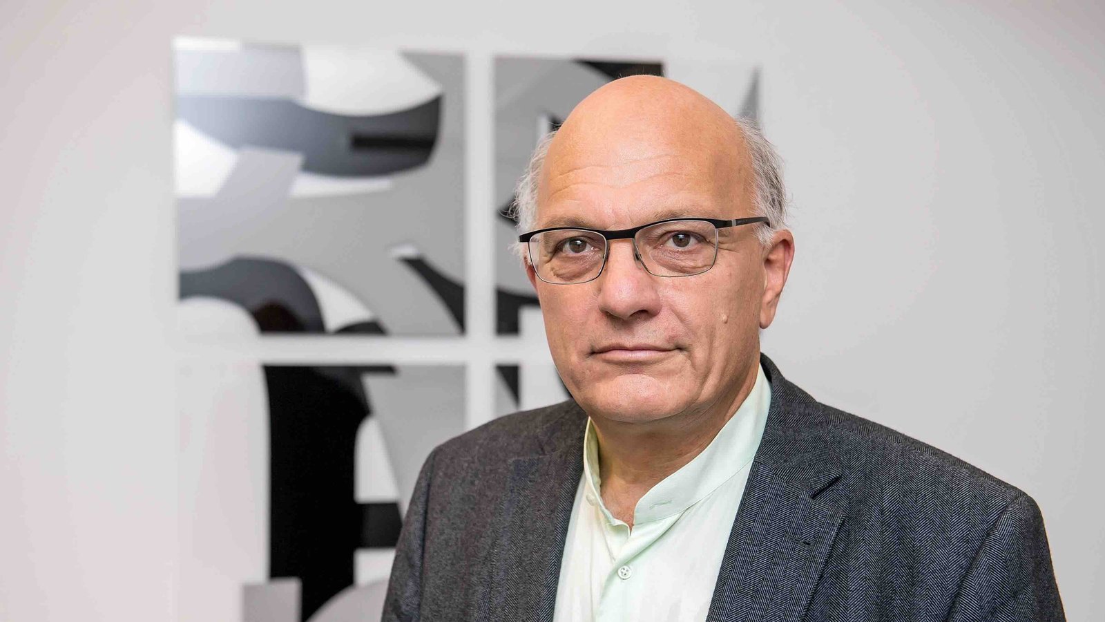 Das Foto zeigt Christian Staffa. Er trägt ein weißes Hemd und ein graues Jackett. Der ältere Mann hat eine Halbglatze und trägt eine Brille.