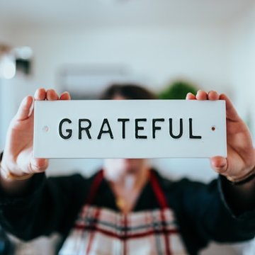Person hält Schild auf dem "Grateful" (Dankbar) steht