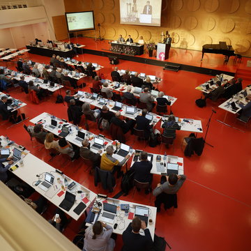 Menschen sitzen in einem Saal an langen weißen Tischen. Das Bild zeigt die Tagung der Frühjahrssynode der eEangelischen Landeskirche in Württemberg