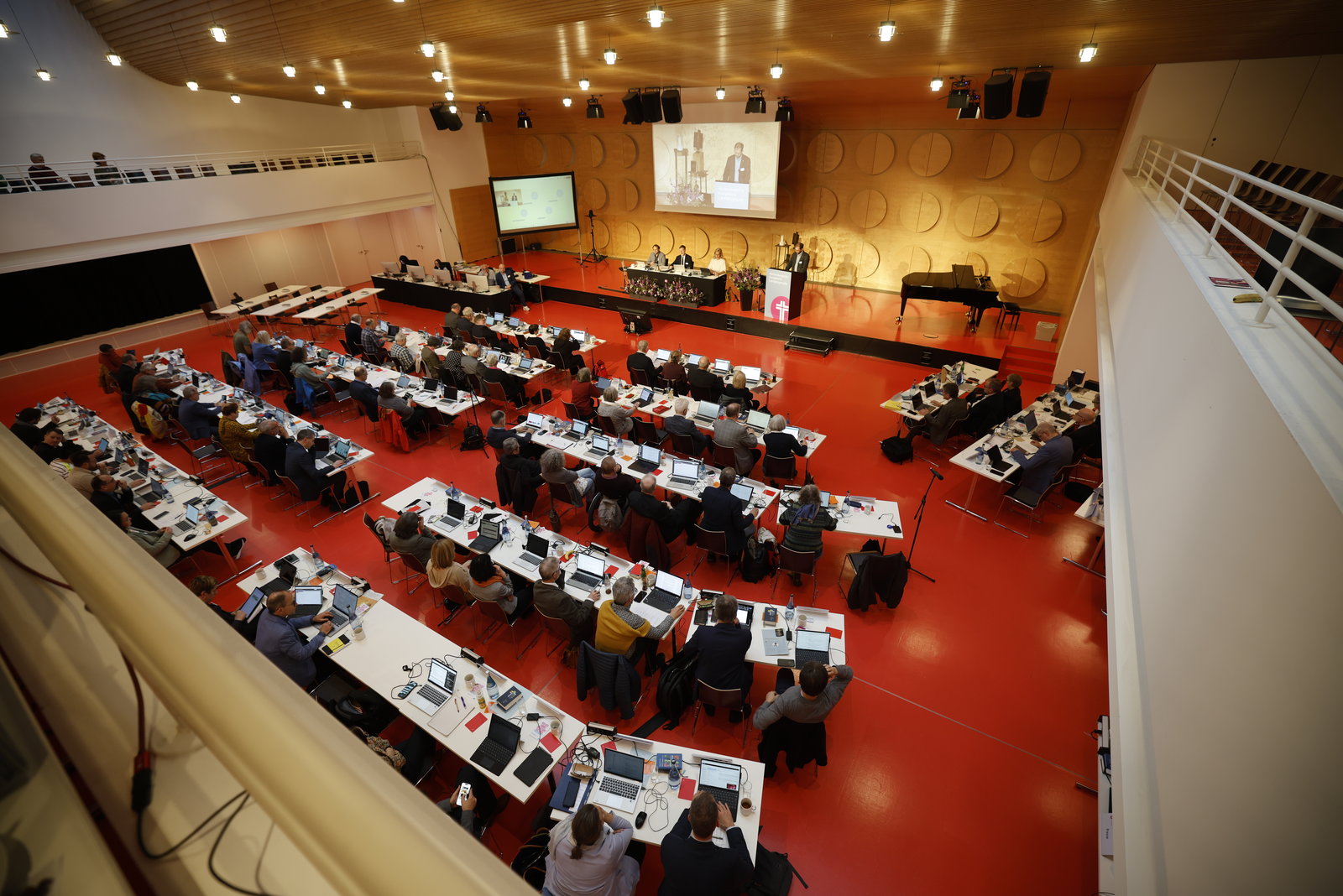 Menschen sitzen in einem Saal an langen weißen Tischen. Das Bild zeigt die Tagung der Frühjahrssynode der eEangelischen Landeskirche in Württemberg