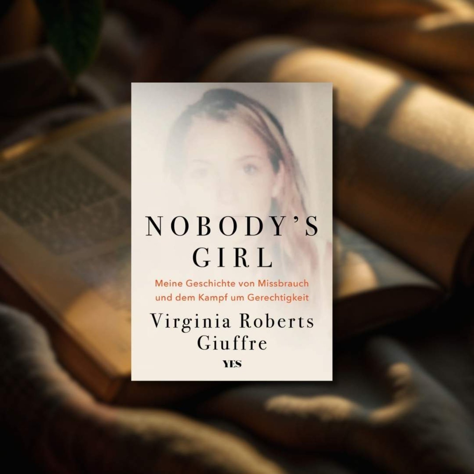 Buchtipp: „Nobody‘s Girl“ im Vordergrund. Im Hintergrund befindet sich ein Buch auf einer Decke.