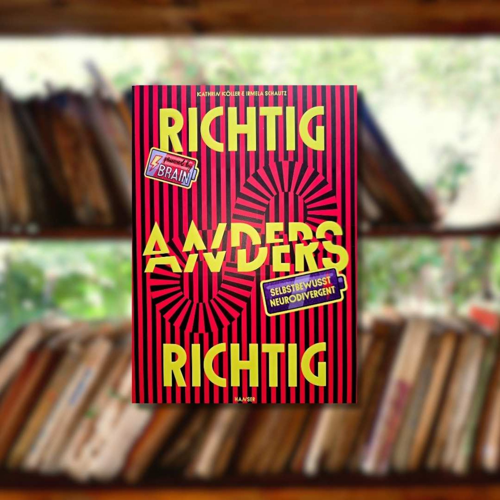 Buchtipp: „Richtig Anders – Anders Richtig.“ im Vordergrund. Im Hintergrund ist ein Bücherregal mit alten Büchern zu sehen.