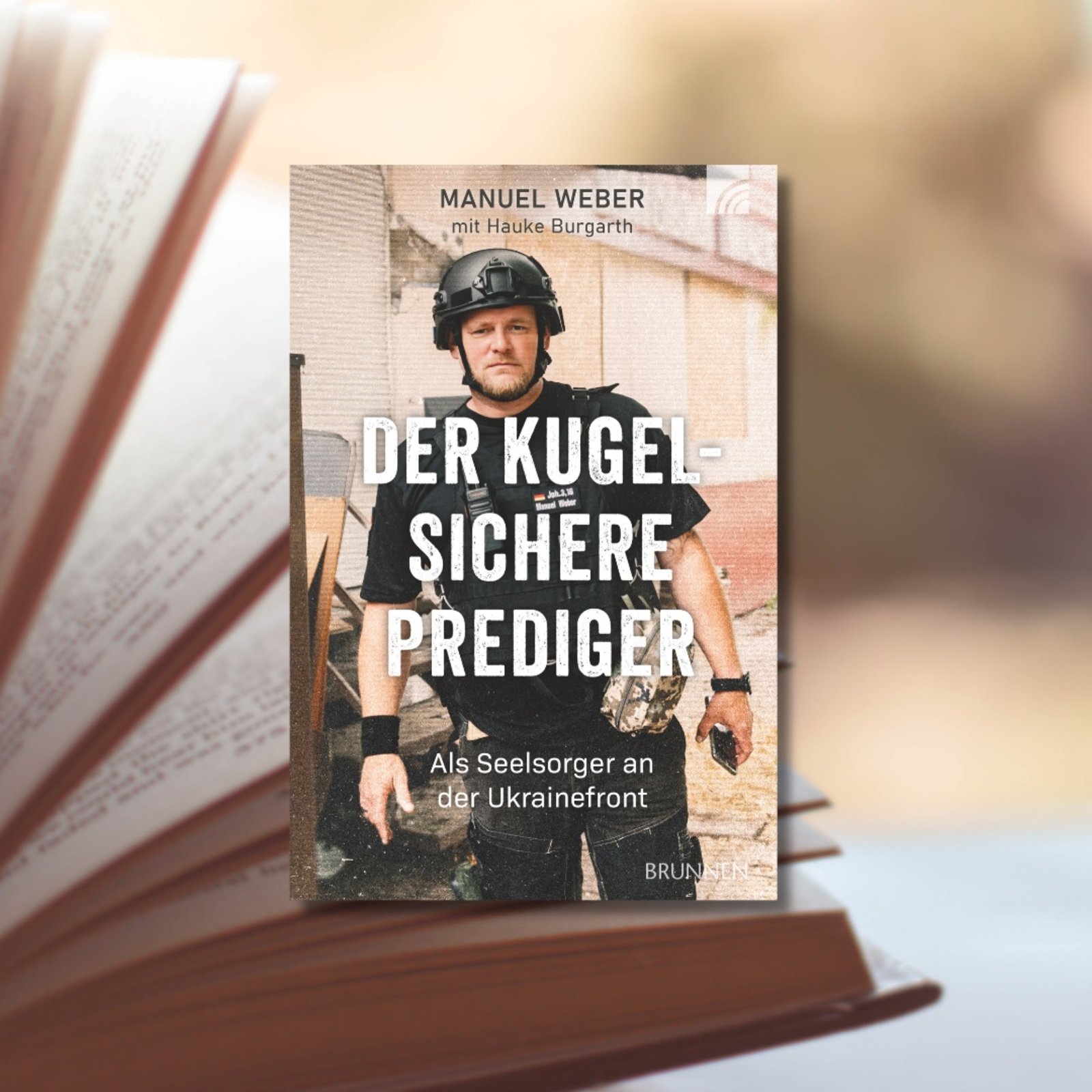 Cover des Buches „Der kugelsichere Prediger. Als Seelsorger an der Ukrainefront.“ von Manuel Weber mit Hauke Burgarth im Vordergrund, ein aufgeschlagenes Buch im Hintergrund.