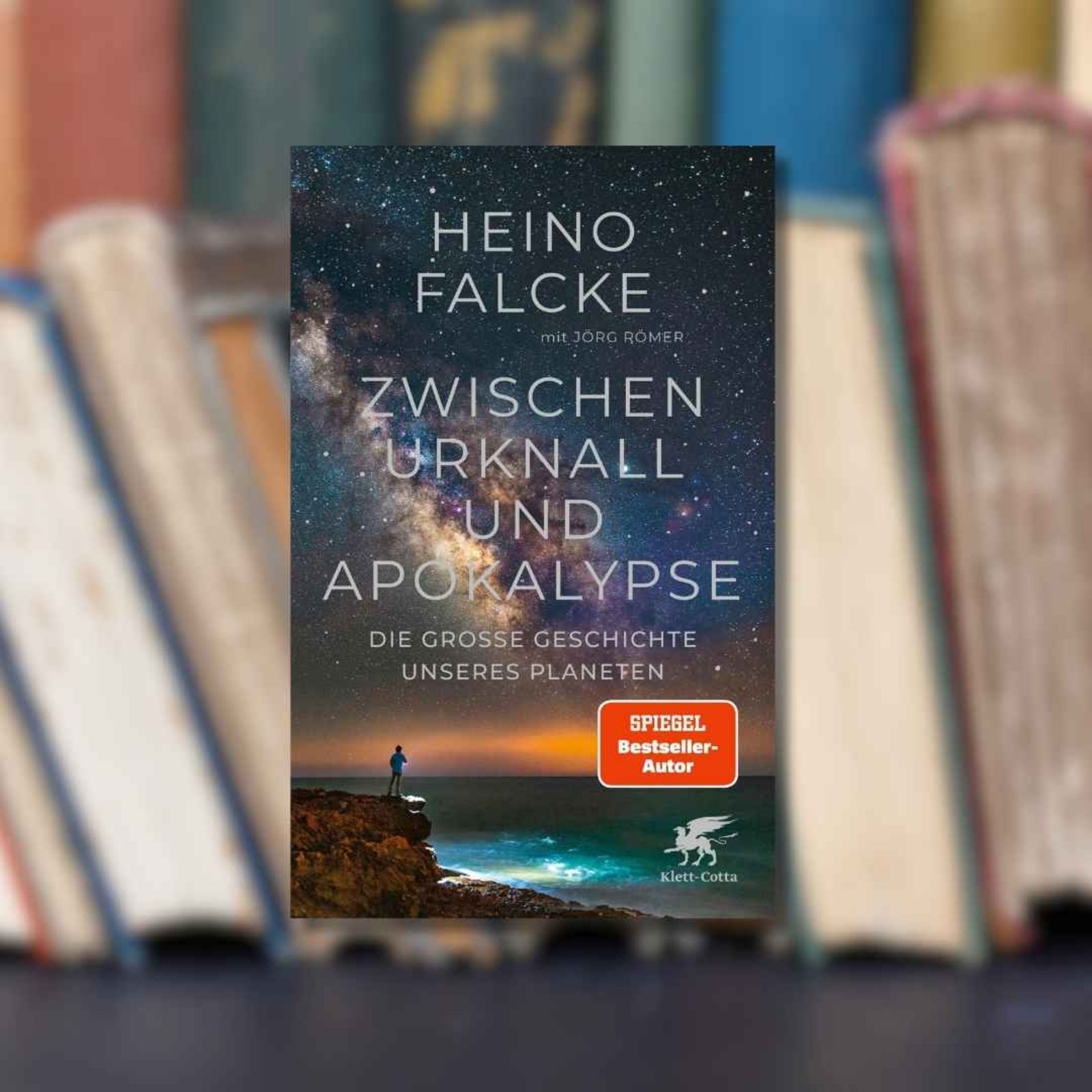 Buchtipp: „Zwischen Urknall und Apokalypse“ im Vordergrund. Im Hintergrund ist eine Reihe an alten Büchern zu sehen.