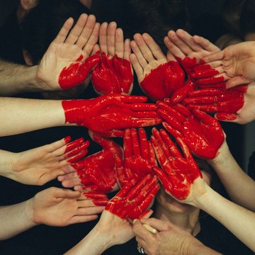 viele Hände, die sich durch rote Farbe angemalt zu einem Herz formen