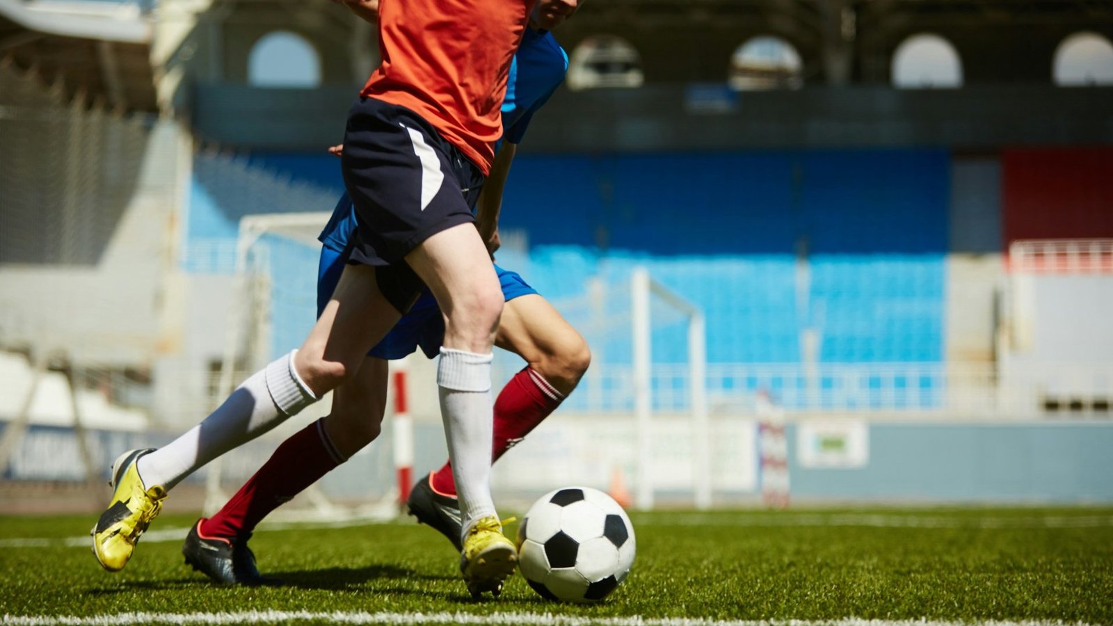 Zwei junge Männer spielen Fußball auf einem Rasen. Sie kicken einen schwarz-weißen Ball