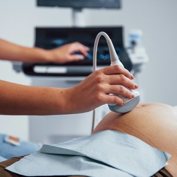 Der Bauch einer Schwangeren wird von einer Ärztin mit einem Ultraschallgerät untersucht.