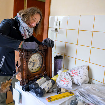 Eine Frau hat eine alte Walduhr in der Hand.