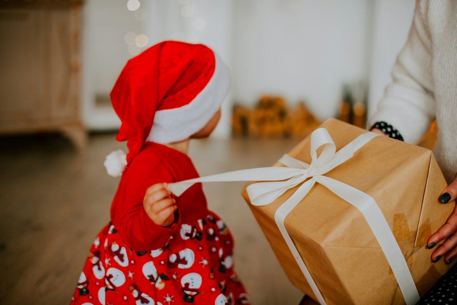 Kind mit Nikolausmütze packt Geschenk aus