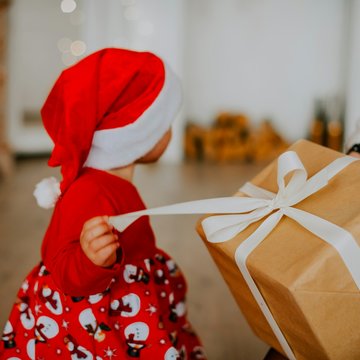Kind mit Nikolausmütze packt Geschenk aus