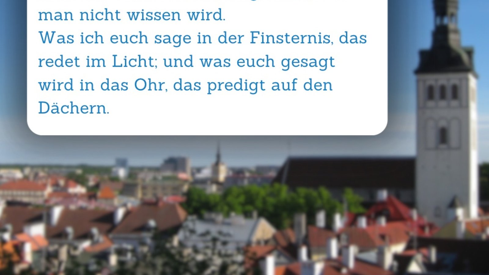 Bibelspruch im Vordergrund, im Hintergrund ist eine Gemeinde mit einem hohen Kirchturm zu sehen.