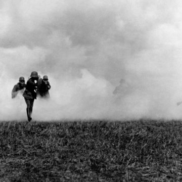 Man sieht Soldaten auf einem Feld während eines Gasangriffs. Es ist ein Schwarz-Weiß-Foto