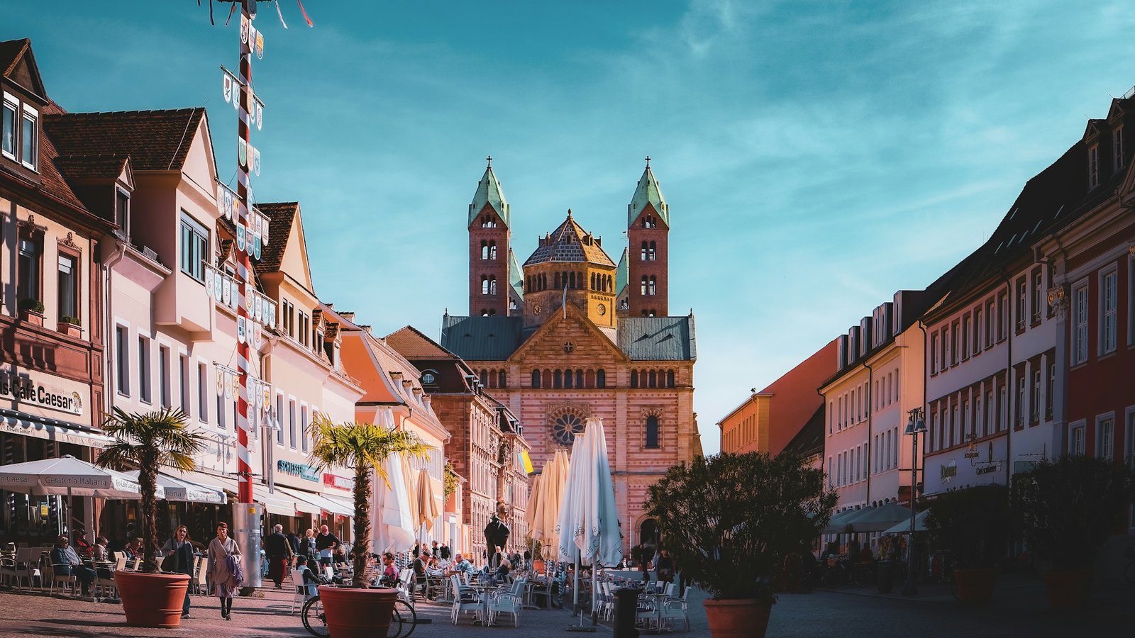 Die Innenstadt von Speyer, eine Straße führt auf eine Kirche mit zwei Türmen und einer Kuppel zu.