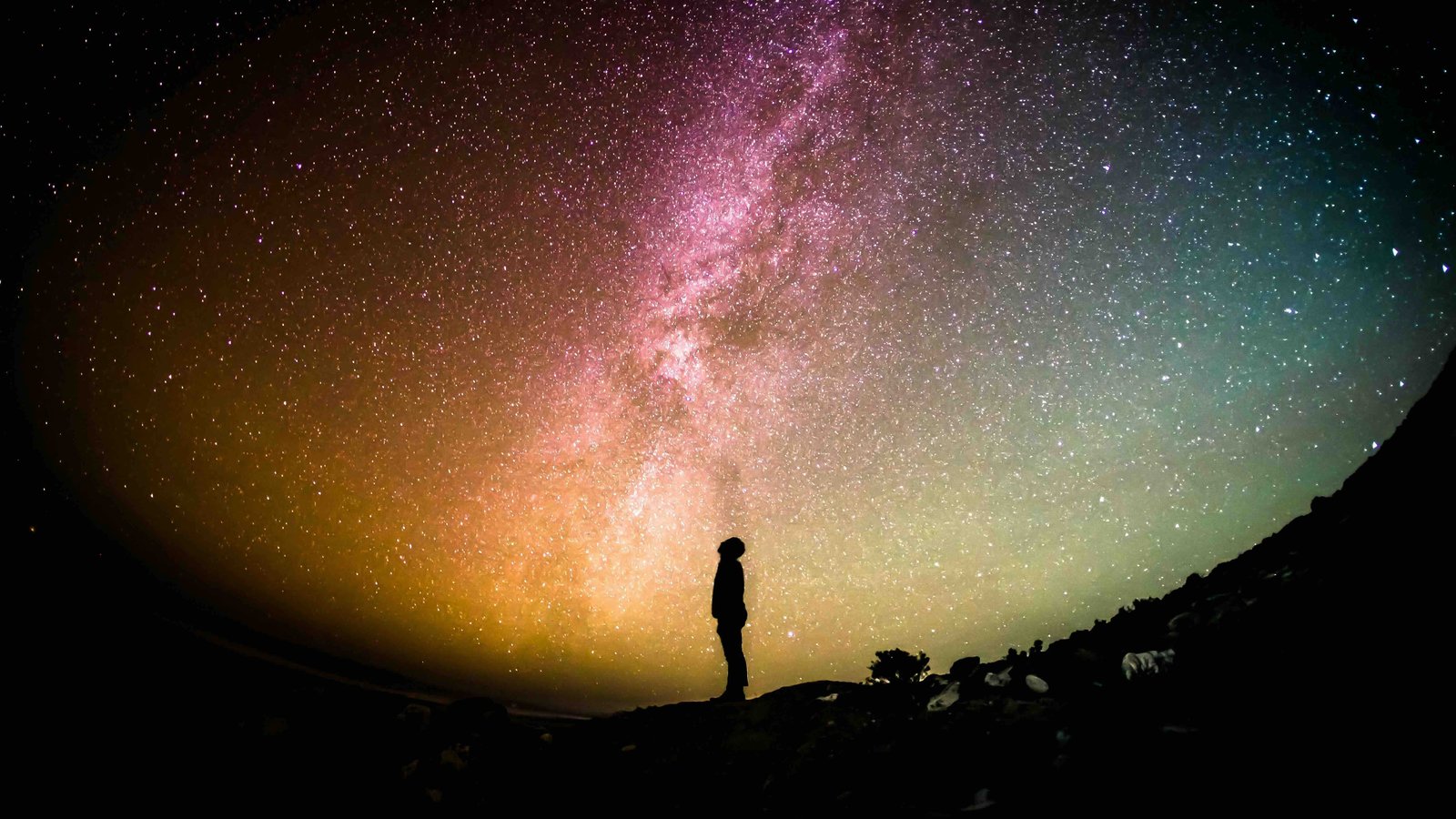 Die Aufnahme zeigt eine Silhouette, die in einen bunten Himmel schaut.