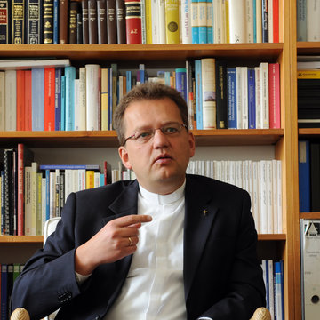 Uwe Gräbe sitzt vor einem Bücherregal