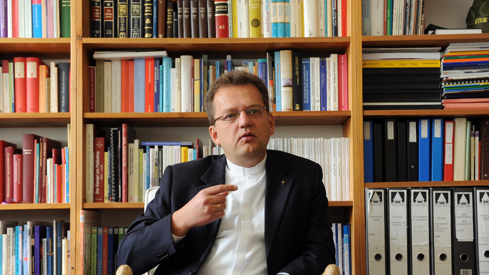 Uwe Gräbe sitzt vor einem Bücherregal