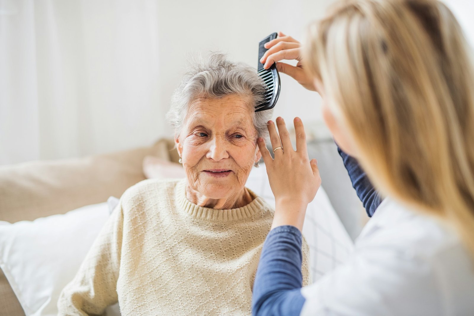 Pflegekraft kämmt Seniorin die Haare