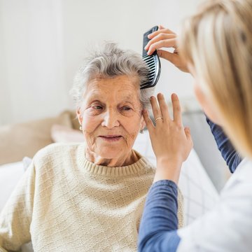 Pflegekraft kämmt Seniorin die Haare