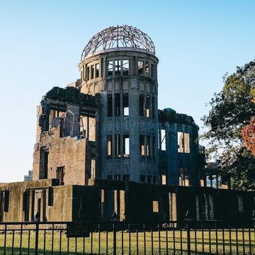Bäume stehen um eine Ruine aus Beton herum. Die Kuppel des verfallenen Gebäudes ist aus Metall gefertigt. 