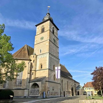 Das Foto zeigt die Johanneskirche in Crailsheim bei Sonnenschein und blauen, leicht bewölktem Himmel.
