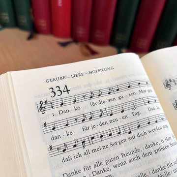 Ein aufgeschlagenes Evangelisches Gesangbuch zeigt Lied Nummer 334 „Danke für diesen guten Morgen”