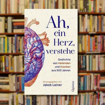 Buchcover "Ah, ein Herz, verstehe" im Vordergrund, im Hintergrund ein Bücherregal.