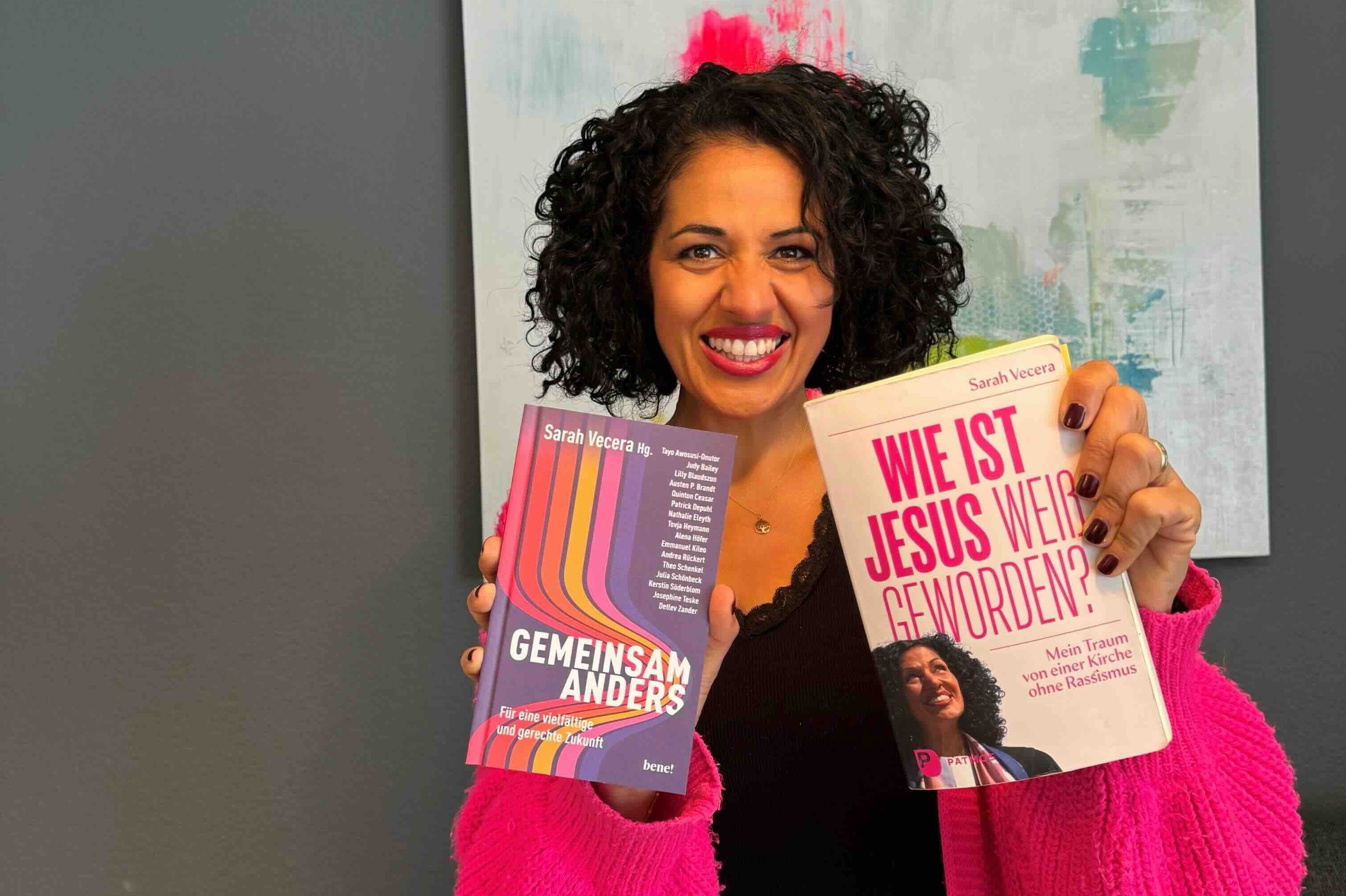 Sarah Vecera hält in der Hand ein Buch und grinst.