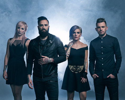 Die Band Skillet (4 Personen) vor einem dunklen Hintergrund