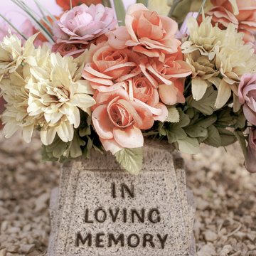 Grabstein auf dem Blumen stehen und die Inschrift "In loving memory"