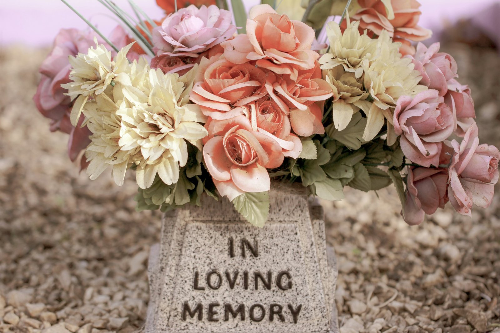 Grabstein auf dem Blumen stehen und die Inschrift "In loving memory"